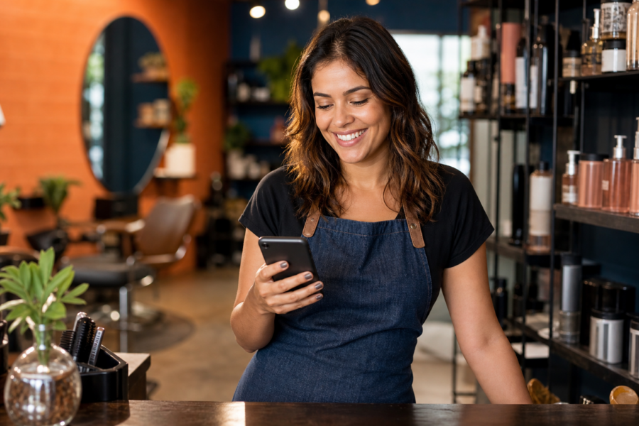 Dona de salão de beleza usando o celular para aprender como usar IA no WhatsApp Business no atendimento a clientes